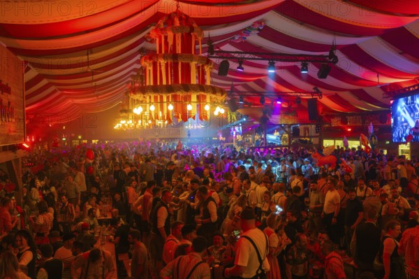 Lively and colourful celebration in a large beer tent full of people and bright decorations, Volksfest Cannstatter Wasen, Sonja Merz Festzelt, Stuttgart, Germany