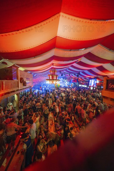 Lively celebration in a decorated beer tent with red and white stripes and lots of people, Cannstatter Wasen folk festival, Sonja Merz Festzelt, Stuttgart, Germany