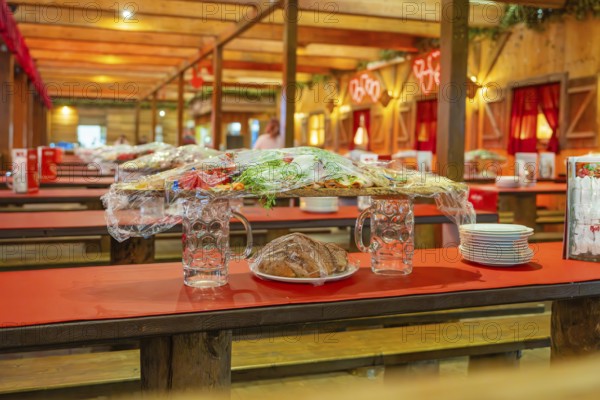 Covered food and beer mugs on red tables in a traditionally decorated tent, Volksfest Cannstatter Wasen, Sonja Merz Festzelt, Stuttgart, Germany
