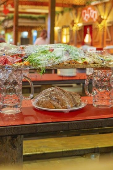 Close-up of beer mugs and packaged food on red tables in the marquee, Cannstatter Wasen folk festival, Sonja Merz marquee, Stuttgart, Germany