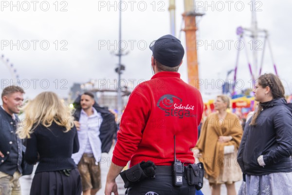 Security guard observing the action on a rainy Oktoberfest site, Cannstatter Wasen public festival, Sonja Merz marquee, Stuttgart, Germany