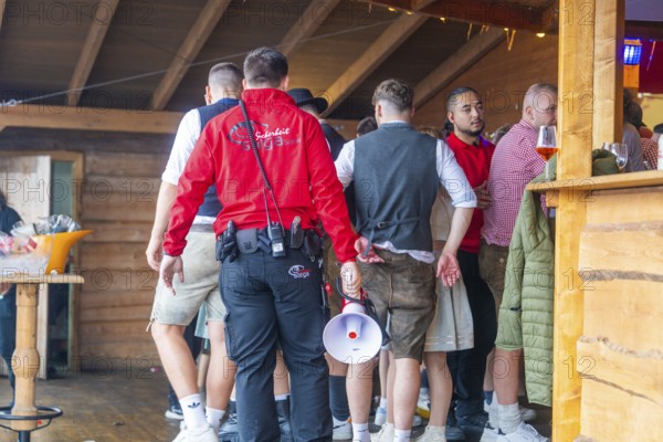 Group of people in traditional traditional costume crowding into an interior with wooden panelling, Cannstatter Wasen folk festival, Sonja Merz marquee, Stuttgart, Germany