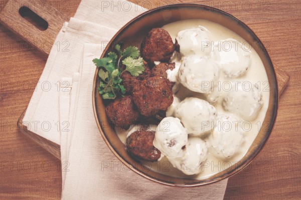 Swedish meatballs in cream sauce, plate on a wooden table, homemade, no people