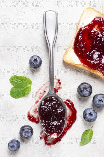 A spoon with blueberry jam, on a white table, breakfast, top view, homemade, no people