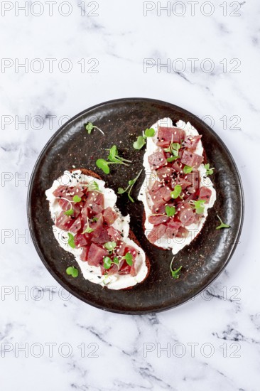 Sandwiches, rye bread with cream cheese, sliced tuna fillet with herbs, breakfast on a black plate, homemade