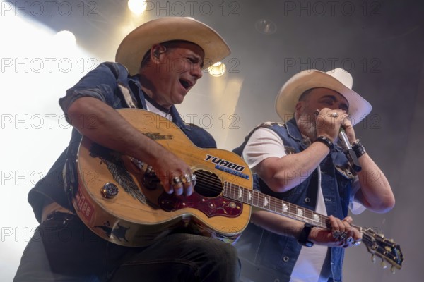 Alec Völkel (Boss Burns), singer, and Malcolm Arison (Hank Williamson), harmonica player of the band The BossHoss during their Back To The Boots Tour 2025 at Capitol Hannover on 3 October 2025