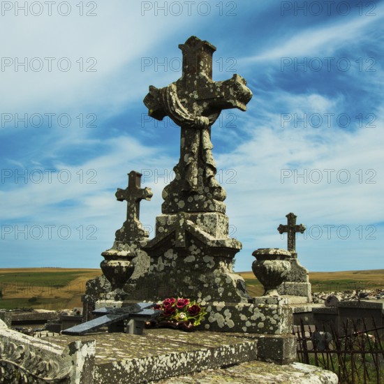 Crosses stand tall against a colorful sunset sky, showcasing the beauty of an ancient cemetery. Cantal. Auvergne Rhone Alpes. France