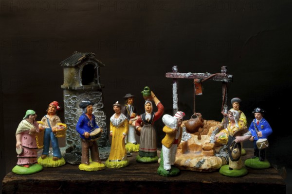 Colorful Provençal terracotta Santons figurines showcase characters engaged in various activities, featuring artisans, farmers, and market sellers in a quaint village setting