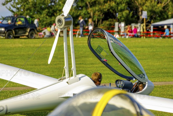 A motorised glider parked at the edge of the airfield with the canopy open during an air show at Rossfeld in Metzingen-Glems, Baden-Württemberg, Germany, for editorial use only