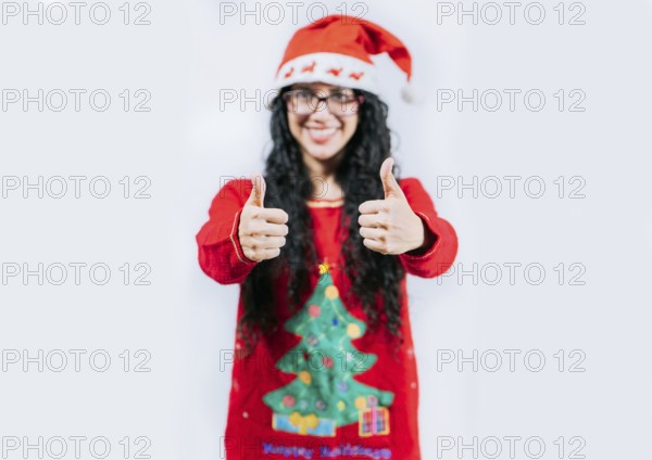 Young woman in Christmas sweater gesturing Ok with thumbs up. isolated. Smiling girl in Christmas sweater giving thumbs up