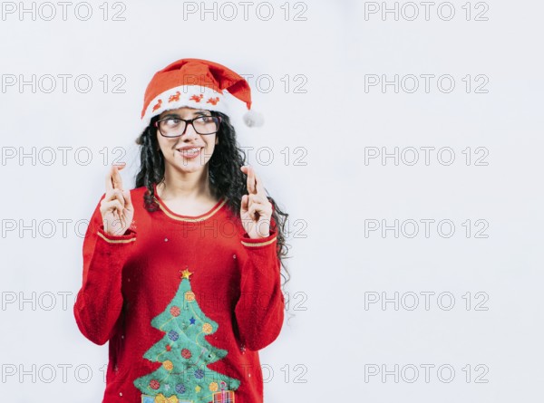 Young woman in Christmas sweater making a wish and crossing fingers. Beautiful girl in Christmas sweater making a wish isolated