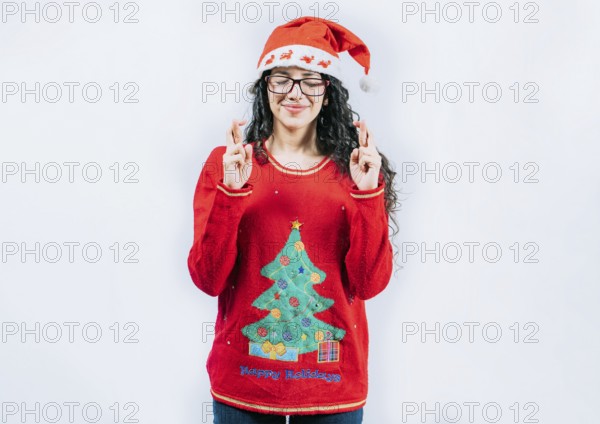 Beautiful girl in Christmas sweater making a wish isolated. Young woman in Christmas sweater making a wish and crossing fingers