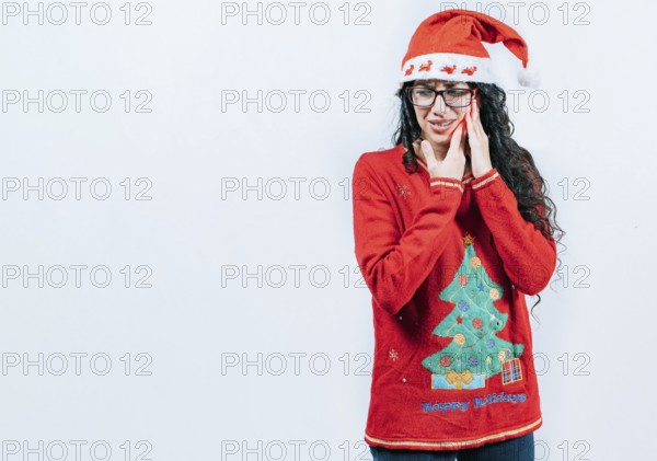 Girl in Christmas dress with toothache on isolated background. Young girl with toothache holding her cheek in Christmas dress