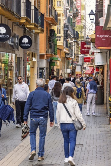Tourists walking on a shopping street with lot of shops in Palma old town, Palma de Mallorca, Mallorca, Spain