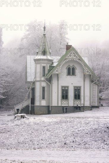 Old idyllic white wooden house with carpentry work a cold winter day with snow and frost, Falköping, Sweden