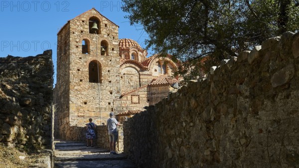 Metropolis, Metropolitan Church of Agios Dimitrios Mystras, Ornamented Byzantine church with trees and two people on a path, Mystras, Mistra, UNESCO World Heritage Site, Medieval Byzantine ruined city, northwest of Sparta, foothills of the Taygetos Mountains, Peloponnese, peninsula, Greece