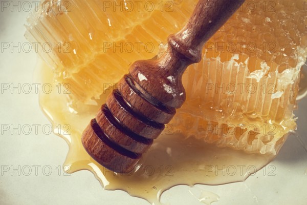 Honeycomb, with a wooden spoon-spindle, on a plate, no people