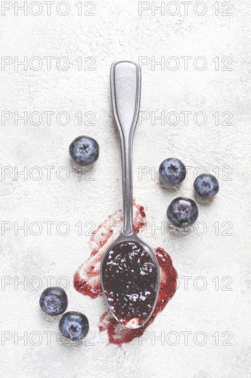 A spoon with blueberry jam, on a white table, breakfast, top view, homemade, no people