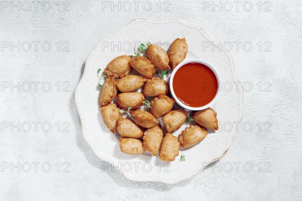 Fried mini chebureks, with sauce, on a decorative plate, hard light, no people