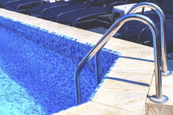 Bright blue swimming pool with ladder under clear sky, perfect for relaxation on a sunny day
