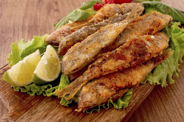 Fried crispy red mullet fish, on a wooden chopping board, with lime, no people