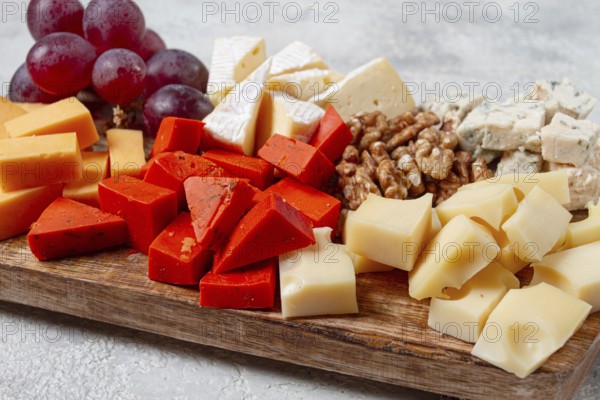 Assorted cheese on a wooden board, with grapes and walnuts, appetizer, no people