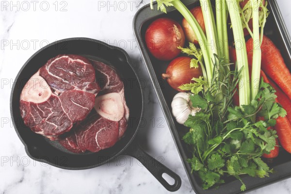 Sknuckle on the bone, raw meat for ossobuco, in a cast-iron pan, baking sheet with vegetables, top view, no people