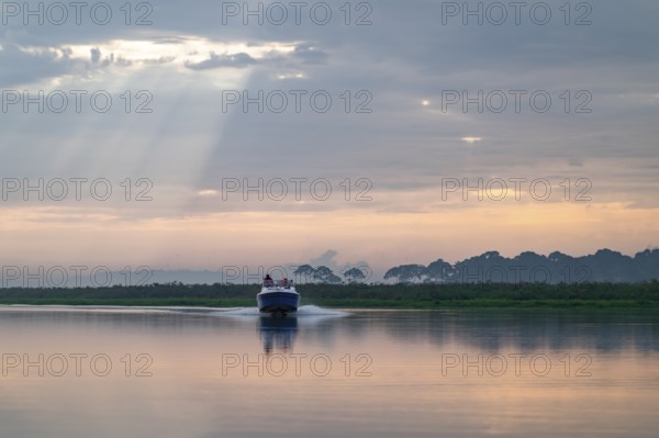 Motorboat on the lake, morning mood, reflection in Lake Victoria, sunbeams and cloudy sky, Mabamba Swamp, Lake Victoria, Uganda