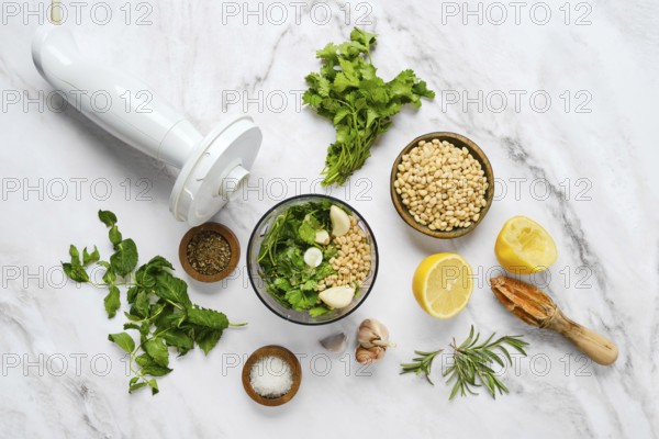 Fresh herbs, pine nuts, garlic, and lemon arranged around a bowl ready for blending. This setting captures the essence of preparing a homemade sauce with vibrant flavors