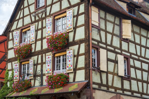 Decorated half-timbered house with ornate windows and flowers in the old town centre of Kaysersberg