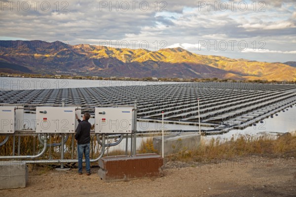 Park City, Utah - Floating solar panels provide power for Mountain Regional Water. The solar array is on the raw water storage pond at the water utility's Signal Hill Treatment Plant. Chris Braun checks the inverter, which converts DC power to AC