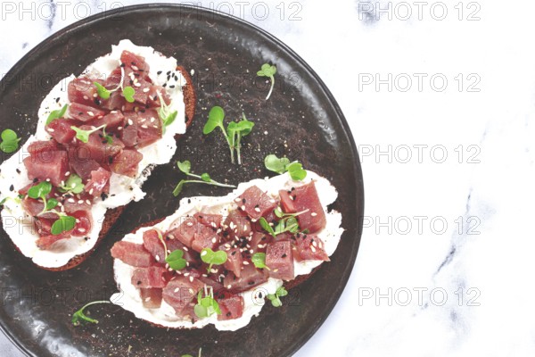 Sandwiches, rye bread with cream cheese, sliced tuna fillet with herbs, breakfast on a black plate, homemade