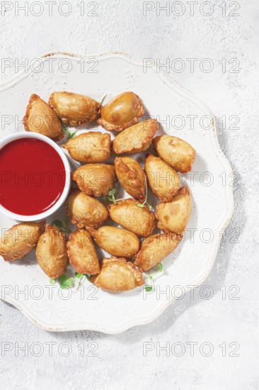 Fried mini chebureks, with sauce, on a decorative plate, hard light, no people