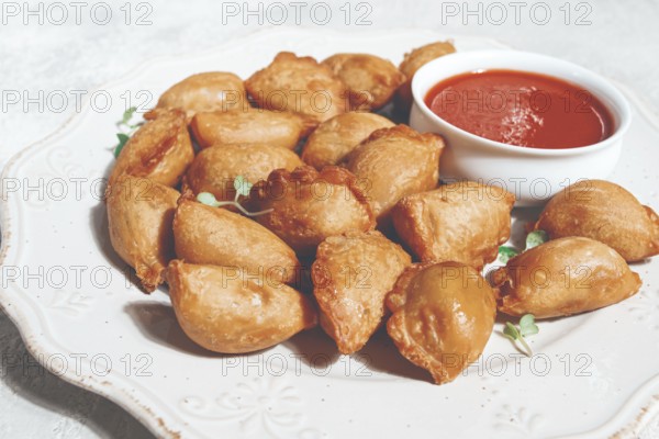 Fried mini chebureks, with sauce, on a decorative plate, hard light, no people