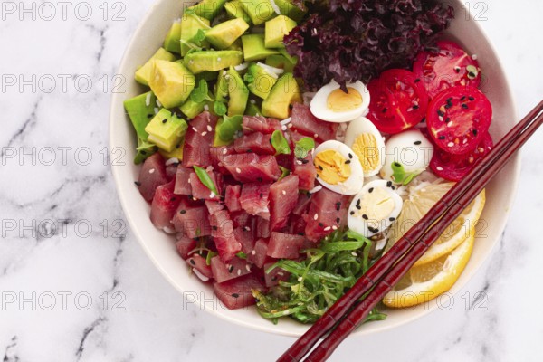 Fresh poke bowl, with tuna, avocado, and vegetables, served on a white plate