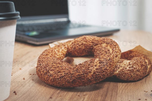 Simits with coffee on a wooden table, with a laptop, in a cozy working environment, snack, breakfast, no people