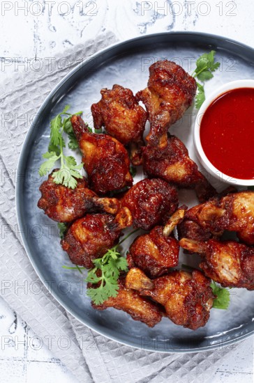 Crispy pieces of fried chicken, on a plate with sauce and herbs, in a modern kitchen environment, there are no people