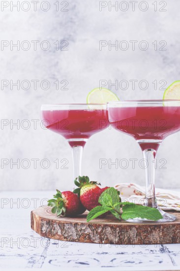 Refreshing cocktail in an elegant glass with lime and strawberries, sunshine, no people