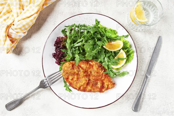 Milanese chicken, Crispy breaded chicken served, with fresh herbs, and lemon wedges