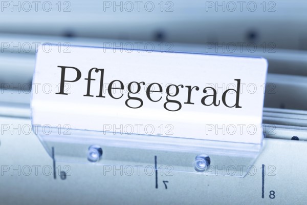 (Photomontage) Sign with the inscription PFLEGEGRAD on a suspension file folder
