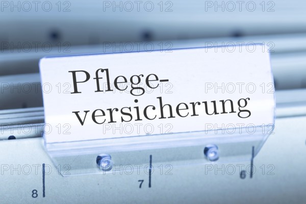 (Photomontage) Sign with the inscription PFLEGEVERSICHERUNG on a suspension file index