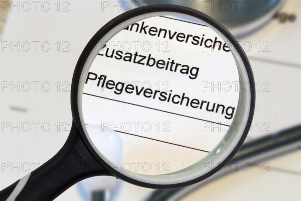 (Photomontage) Close-up of the word PFLEGEVERSICHERUNG on a document, enlarged with a magnifying glass