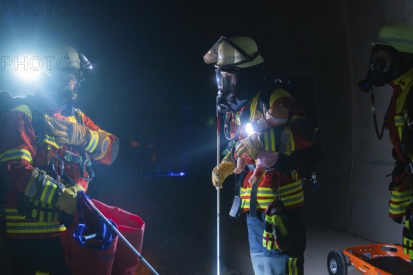 Firefighters in action on rails, equipped with helmets and torches, fire drill in the new construction tunnel of the Hermann Hesse railway, Ostelsheim, district of Calw, Germany