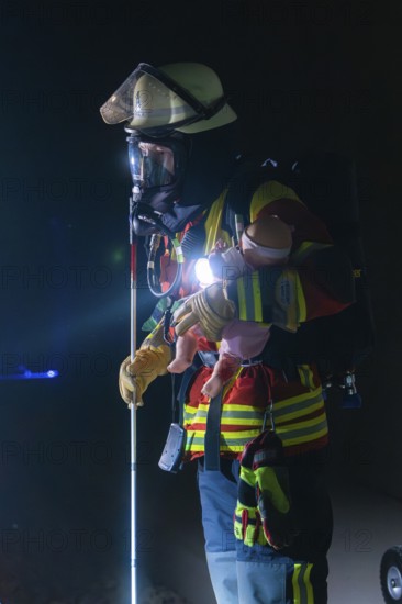 Firefighter with breathing mask and child dummy during a night-time operation, firefighting exercise in the new tunnel of the Hermann Hesse railway, Ostelsheim, Calw district, Germany