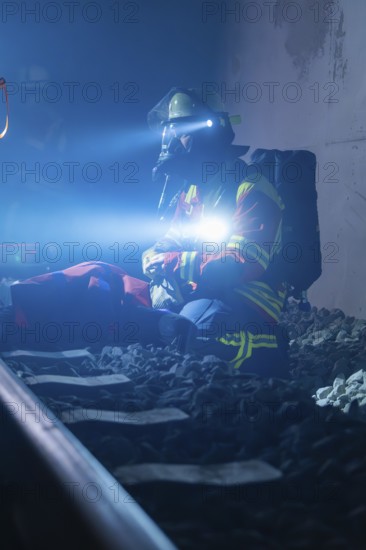 Rescue worker sitting on rails with helmet and breathing mask in dark surroundings, fire brigade exercise in the new tunnel of the Hermann Hesse railway, Ostelsheim, district of Calw, Germany