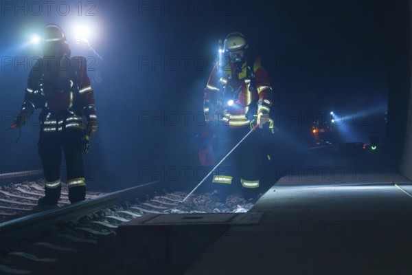 Firefighters working on railway tracks at night with torches and safety equipment, firefighting exercise in the new construction tunnel of the Hermann Hesse railway, Ostelsheim, Calw district, Germany