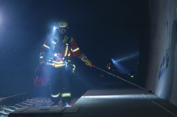 Fireman on a railway platform, at work in the evening with a torch, fire drill in the new construction tunnel of the Hermann Hessebahn, Ostelsheim, district of Calw, Germany