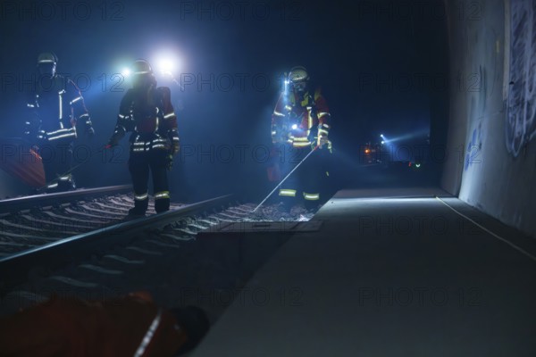Three firefighters walking along a tunnel wall, torch lit, fire drill in the new tunnel of the Hermann Hesse railway, Ostelsheim, district of Calw, Germany