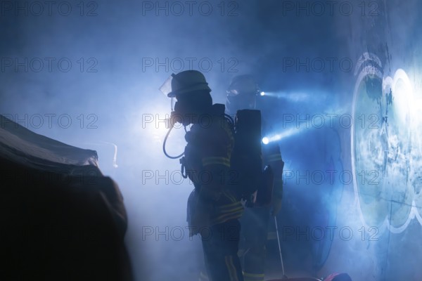 Firefighters in protective suits work in the fog, beams of light cut through the smoke, firefighting exercise in the new construction tunnel of the Hermann Hesse railway, Ostelsheim, district of Calw, Germany