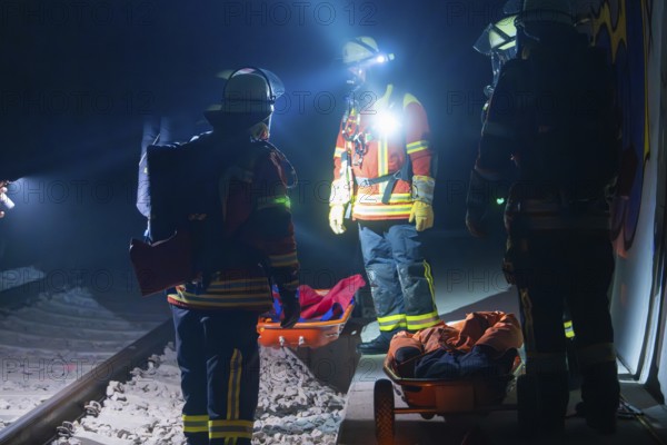 Group of firefighters at night on railway tracks with rescue stretchers, firefighting exercise in the new construction tunnel of the Hermann Hesse railway, Ostelsheim, district of Calw, Germany